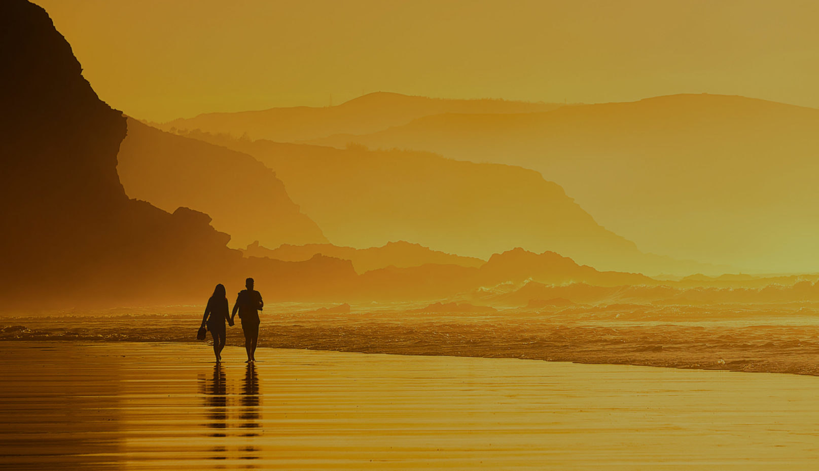 Couple walking in the beach at the sunset