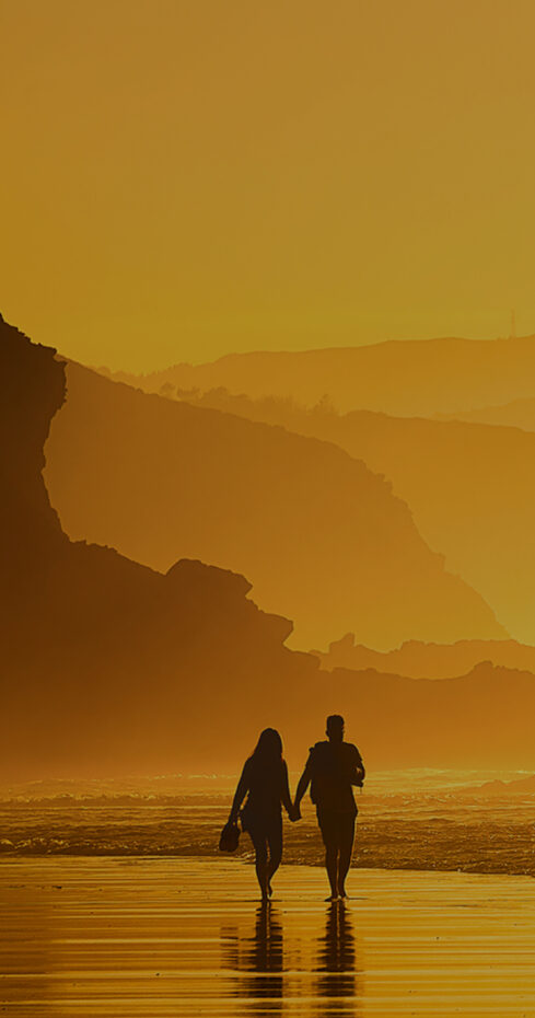 Couple walking in the beach at the sunset